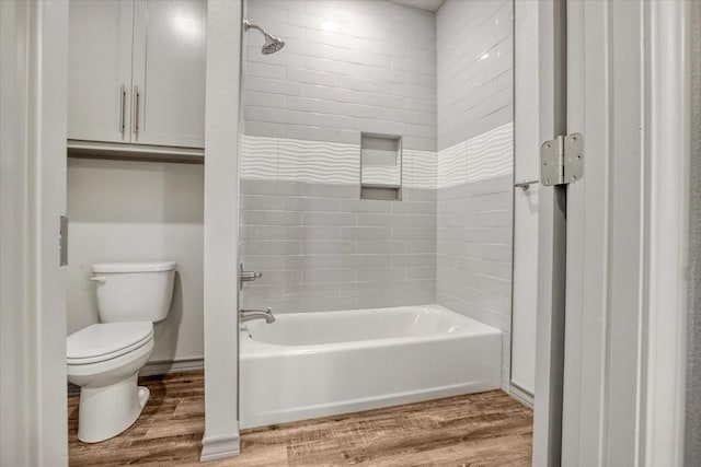 bathroom with tiled shower / bath, wood-type flooring, and toilet