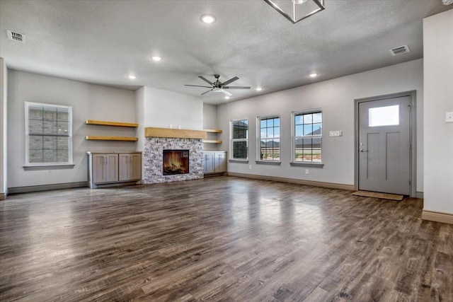 unfurnished living room featuring ceiling fan, a textured ceiling, a fireplace, and dark hardwood / wood-style flooring