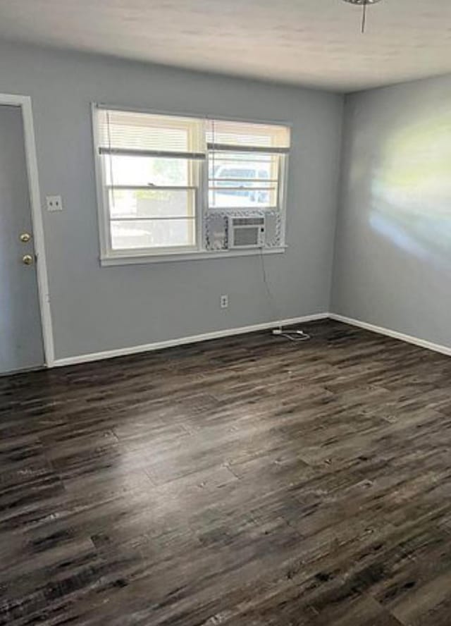 empty room featuring cooling unit, plenty of natural light, and dark hardwood / wood-style floors