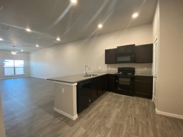 kitchen featuring sink, dark wood-type flooring, black appliances, and kitchen peninsula