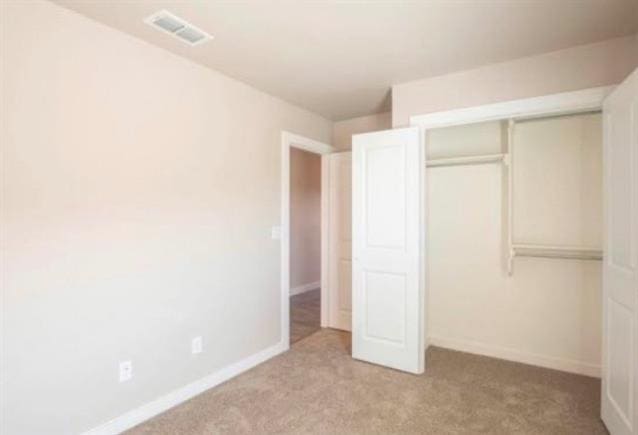 unfurnished bedroom with light carpet and a closet