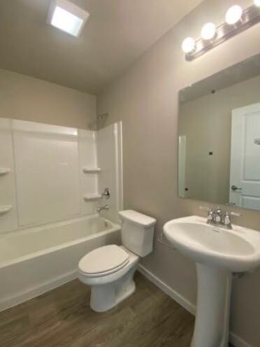 bathroom featuring hardwood / wood-style floors, vaulted ceiling, bathing tub / shower combination, and toilet