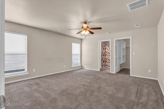 7024 34th Pl, Lubbock, TX 79407 - unfurnished bedroom featuring carpet floors, a walk in closet, baseboards, and a ceiling fan