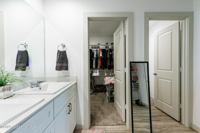 7415 8th St, Lubbock, TX 79416 - bathroom with wood finished floors, double vanity, a spacious closet, and baseboards