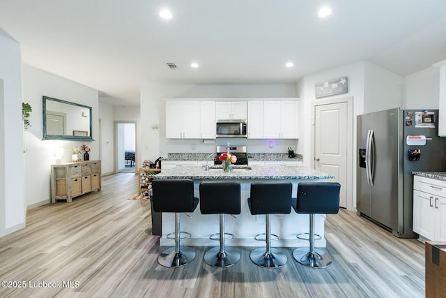 7415 8th St, Lubbock, TX 79416 - kitchen featuring appliances with stainless steel finishes, light stone counters, white cabinetry, recessed lighting, and light wood-style floors