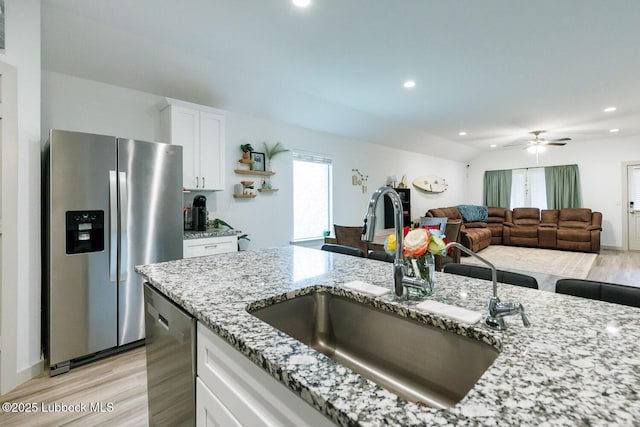 7415 8th St, Lubbock, TX 79416 - kitchen with stainless steel appliances, a sink, light wood-type flooring, light stone counters, and white cabinets
