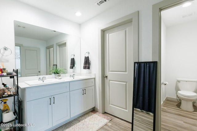 7415 8th St, Lubbock, TX 79416 - full bathroom with wood finished floors, double vanity, toilet, recessed lighting, and baseboards