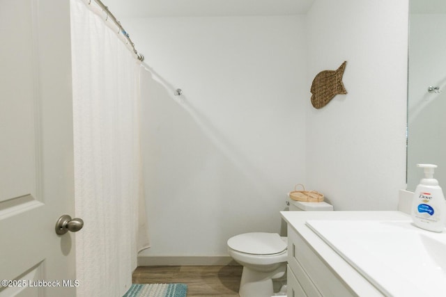 7415 8th St, Lubbock, TX 79416 - bathroom with toilet, vanity, wood finished floors, a shower with curtain, and baseboards