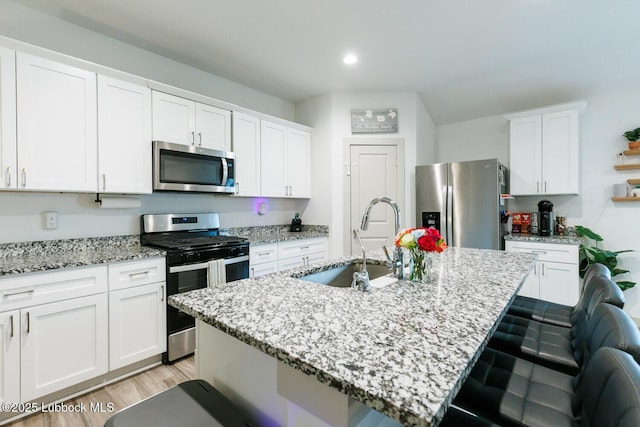 7415 8th St, Lubbock, TX 79416 - kitchen featuring stainless steel appliances, a sink, a kitchen bar, white cabinetry, and a center island with sink