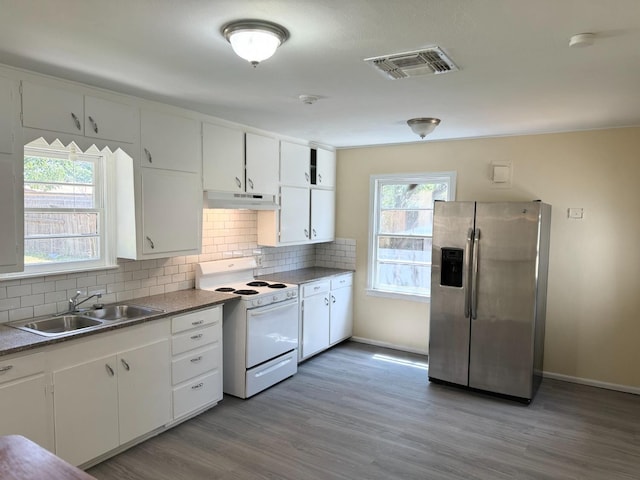 kitchen with sink, white cabinets, stainless steel fridge, backsplash, and electric stove