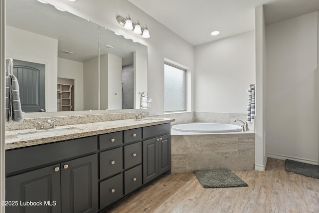 5303 Lehigh St, Lubbock, TX 79416 - full bathroom with double vanity, a bath, wood finished floors, and a walk in closet