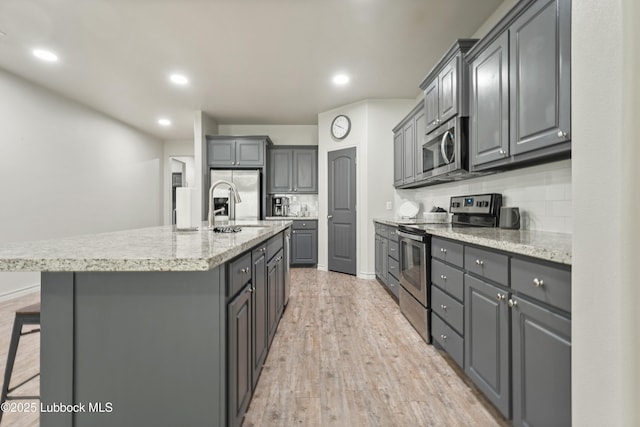 5303 Lehigh St, Lubbock, TX 79416 - kitchen featuring appliances with stainless steel finishes, gray cabinetry, a kitchen island with sink, light wood-type flooring, and recessed lighting