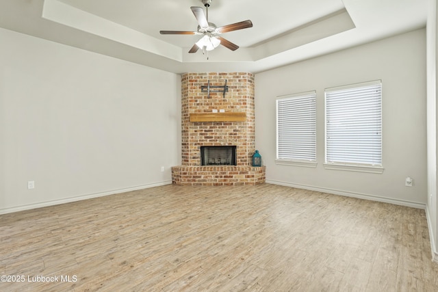 5303 Lehigh St, Lubbock, TX 79416 - unfurnished living room featuring a raised ceiling, wood finished floors, a ceiling fan, and a fireplace