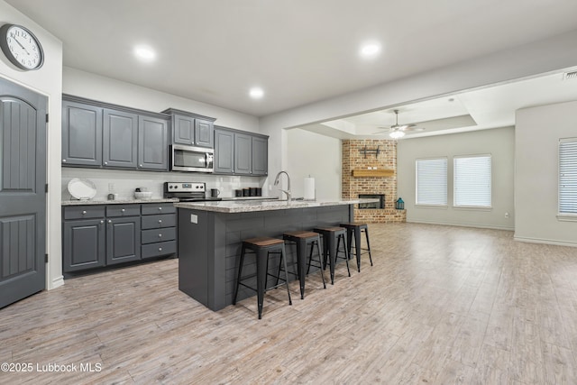 5303 Lehigh St, Lubbock, TX 79416 - kitchen with stainless steel microwave, a ceiling fan, gray cabinetry, open floor plan, and a raised ceiling