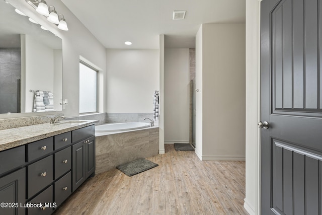 5303 Lehigh St, Lubbock, TX 79416 - bathroom featuring vanity, a garden tub, wood finished floors, a stall shower, and recessed lighting