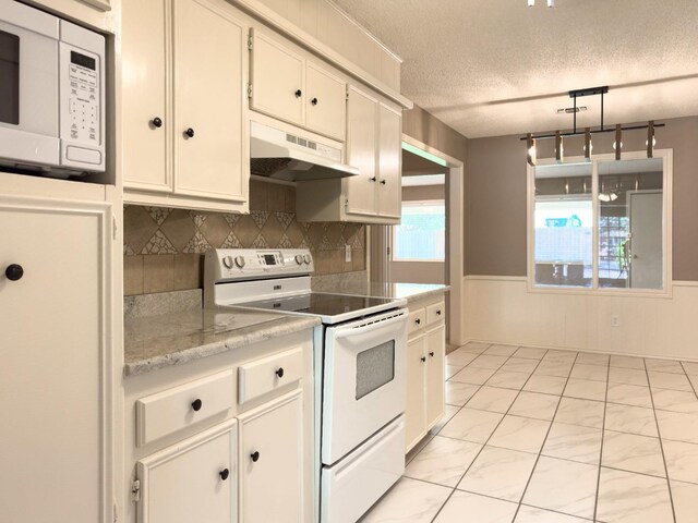 kitchen with white cabinetry, hanging light fixtures, white appliances, light stone counters, and a textured ceiling