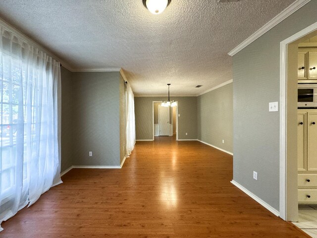 spare room with hardwood / wood-style flooring, ornamental molding, a notable chandelier, and a textured ceiling