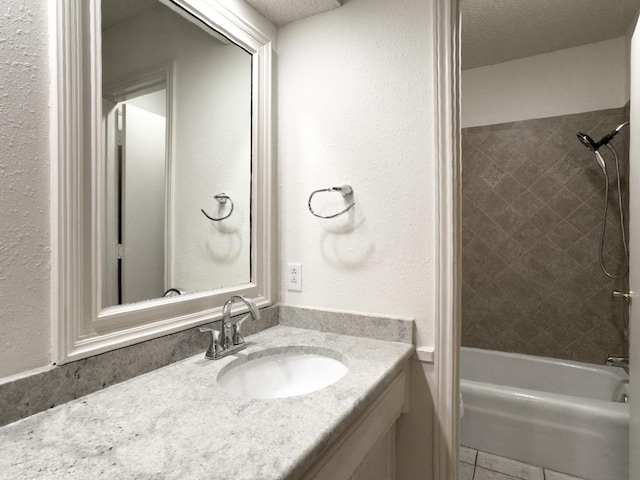 bathroom featuring vanity, tile patterned flooring, a textured ceiling, and tiled shower / bath