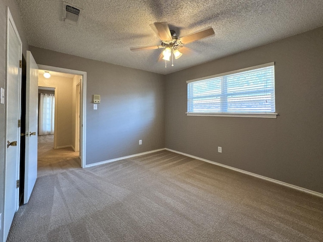 carpeted spare room with a textured ceiling and ceiling fan