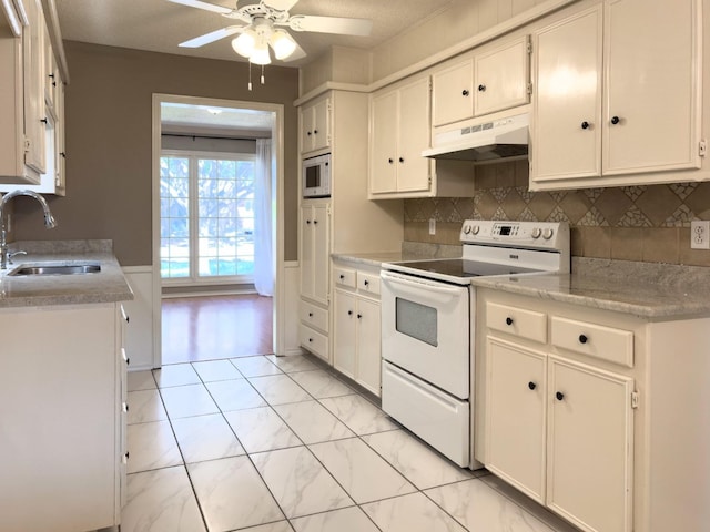 kitchen featuring sink, white appliances, white cabinets, ceiling fan, and backsplash