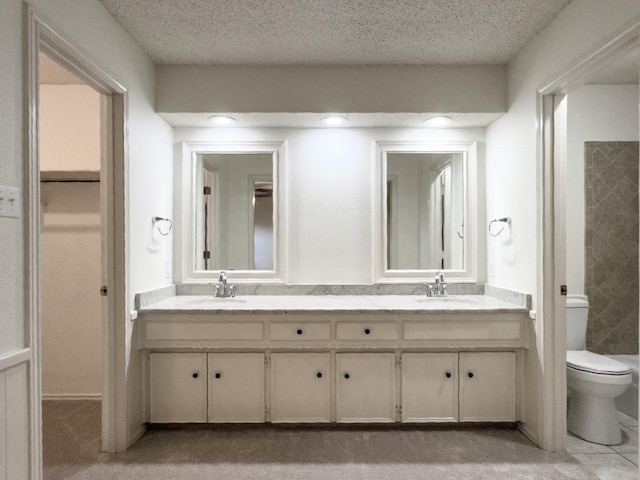 bathroom with vanity, a textured ceiling, and toilet