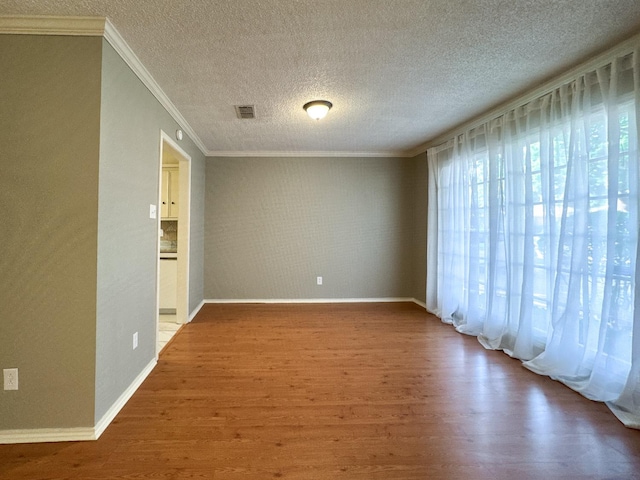 unfurnished room with hardwood / wood-style flooring, ornamental molding, and a textured ceiling