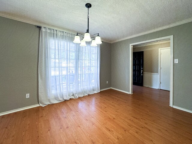 empty room featuring hardwood / wood-style flooring, crown molding, an inviting chandelier, and a textured ceiling