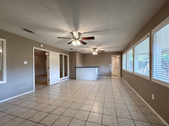 spare room with light tile patterned floors, a textured ceiling, and ceiling fan