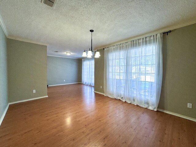 spare room featuring crown molding, hardwood / wood-style floors, a notable chandelier, and a textured ceiling