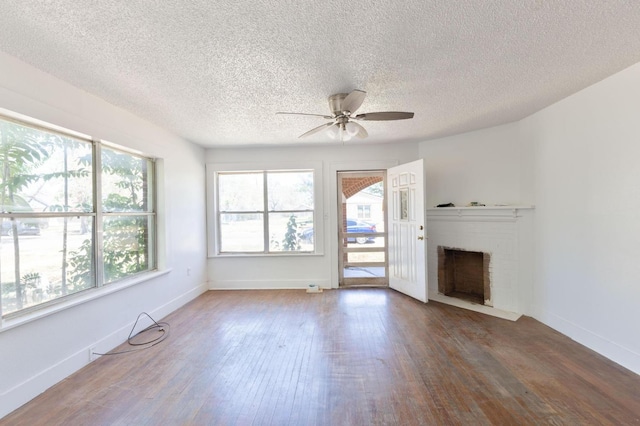 unfurnished living room featuring ceiling fan, a fireplace, dark hardwood / wood-style flooring, and a textured ceiling