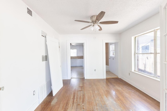 empty room featuring ceiling fan, a textured ceiling, and light hardwood / wood-style flooring