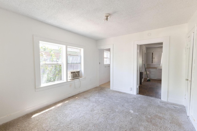 unfurnished bedroom with cooling unit, carpet floors, and a textured ceiling