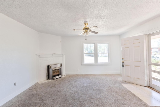 unfurnished living room featuring ceiling fan, a fireplace, light carpet, and a textured ceiling