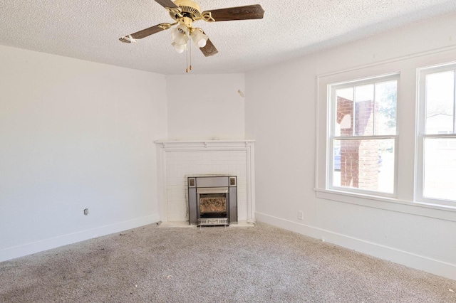 unfurnished living room featuring ceiling fan, carpet floors, a brick fireplace, and a textured ceiling