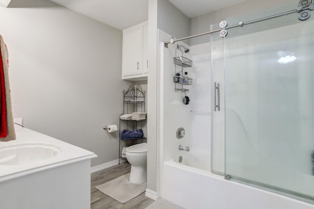 full bathroom with bath / shower combo with glass door, wood-type flooring, toilet, and vanity