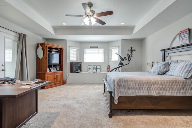 carpeted bedroom with ceiling fan and a tray ceiling