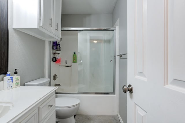 full bathroom featuring vanity, combined bath / shower with glass door, and toilet