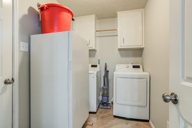 laundry room featuring independent washer and dryer, cabinets, a textured ceiling, and light wood-type flooring