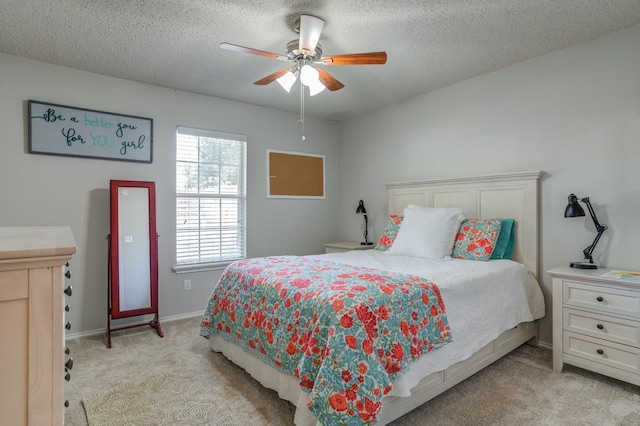 bedroom with ceiling fan, light colored carpet, and a textured ceiling