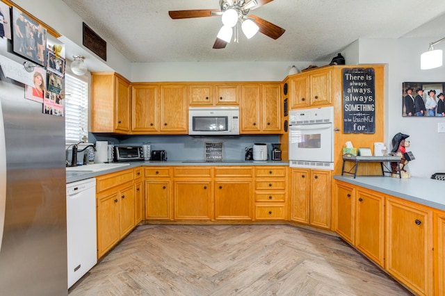 kitchen with sink, white appliances, ceiling fan, light parquet flooring, and a textured ceiling