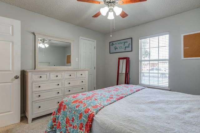 bedroom featuring light carpet, a textured ceiling, and ceiling fan