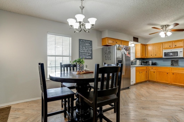 dining space featuring light parquet flooring, ceiling fan with notable chandelier, and a textured ceiling