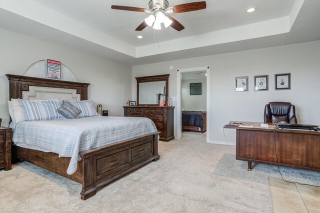 carpeted bedroom with ceiling fan and a tray ceiling