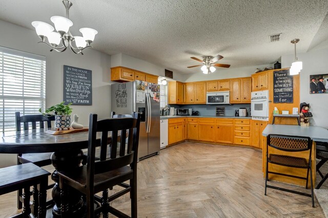 kitchen featuring ceiling fan with notable chandelier, decorative light fixtures, sink, white appliances, and a textured ceiling