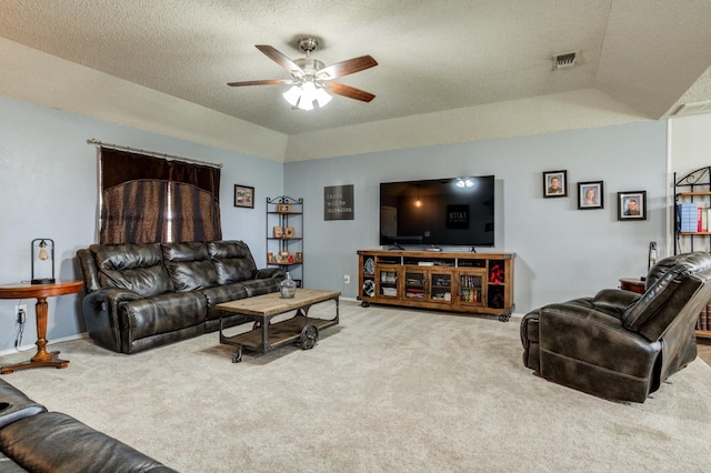 living room featuring ceiling fan, a tray ceiling, a textured ceiling, and carpet flooring