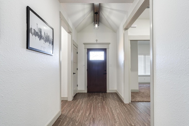 foyer featuring a textured wall, baseboards, lofted ceiling, and wood finished floors