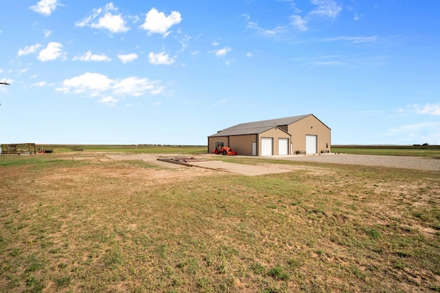 view of yard featuring a garage, an outbuilding, and a rural view