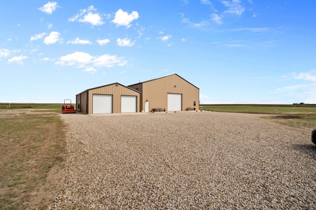 exterior space featuring a garage, an outdoor structure, and a rural view