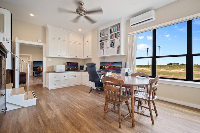 office space with ceiling fan, a wall mounted AC, built in desk, and light wood-type flooring