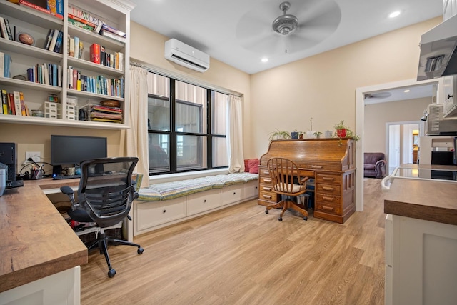 home office with ceiling fan, light hardwood / wood-style floors, and a wall unit AC